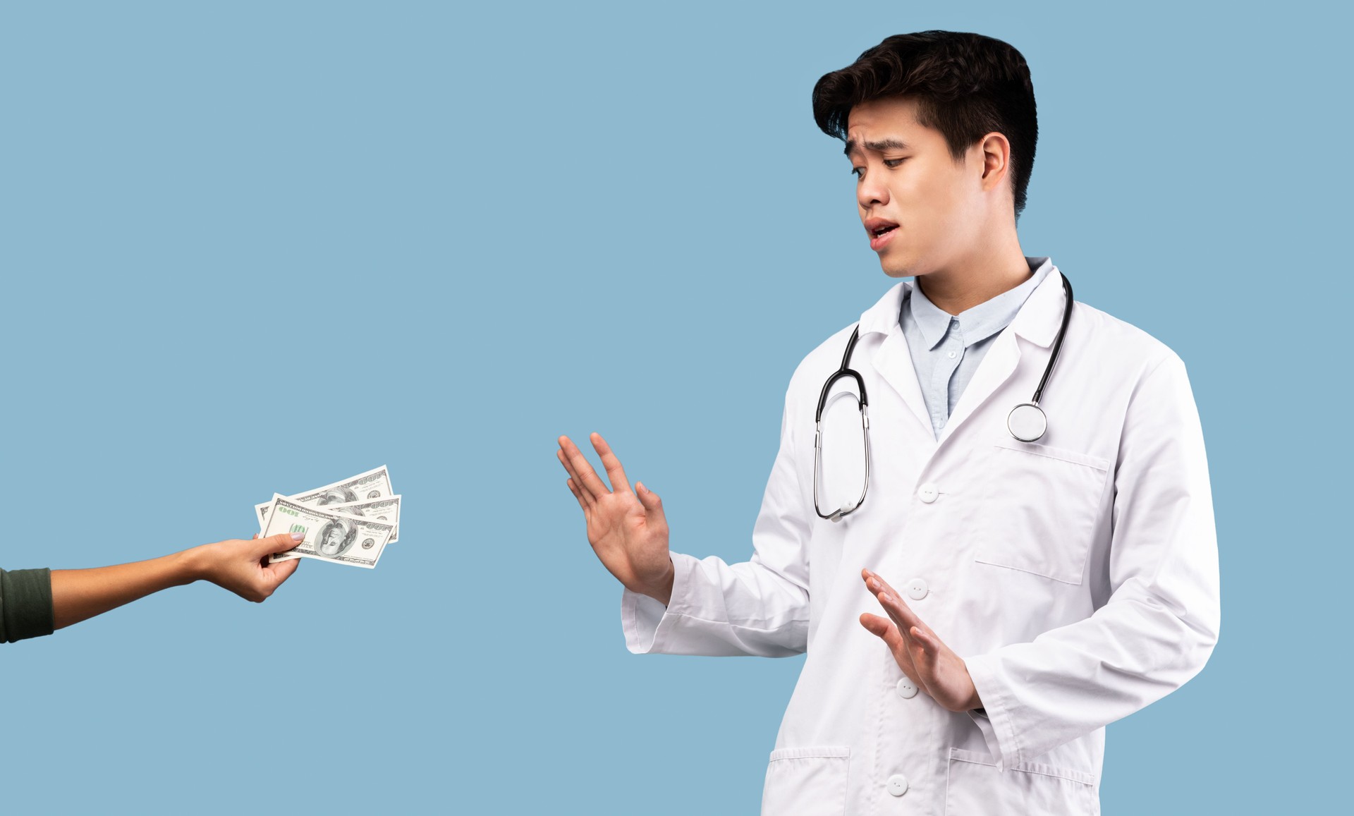 Scared asian male doctor refusing bribe from female patient